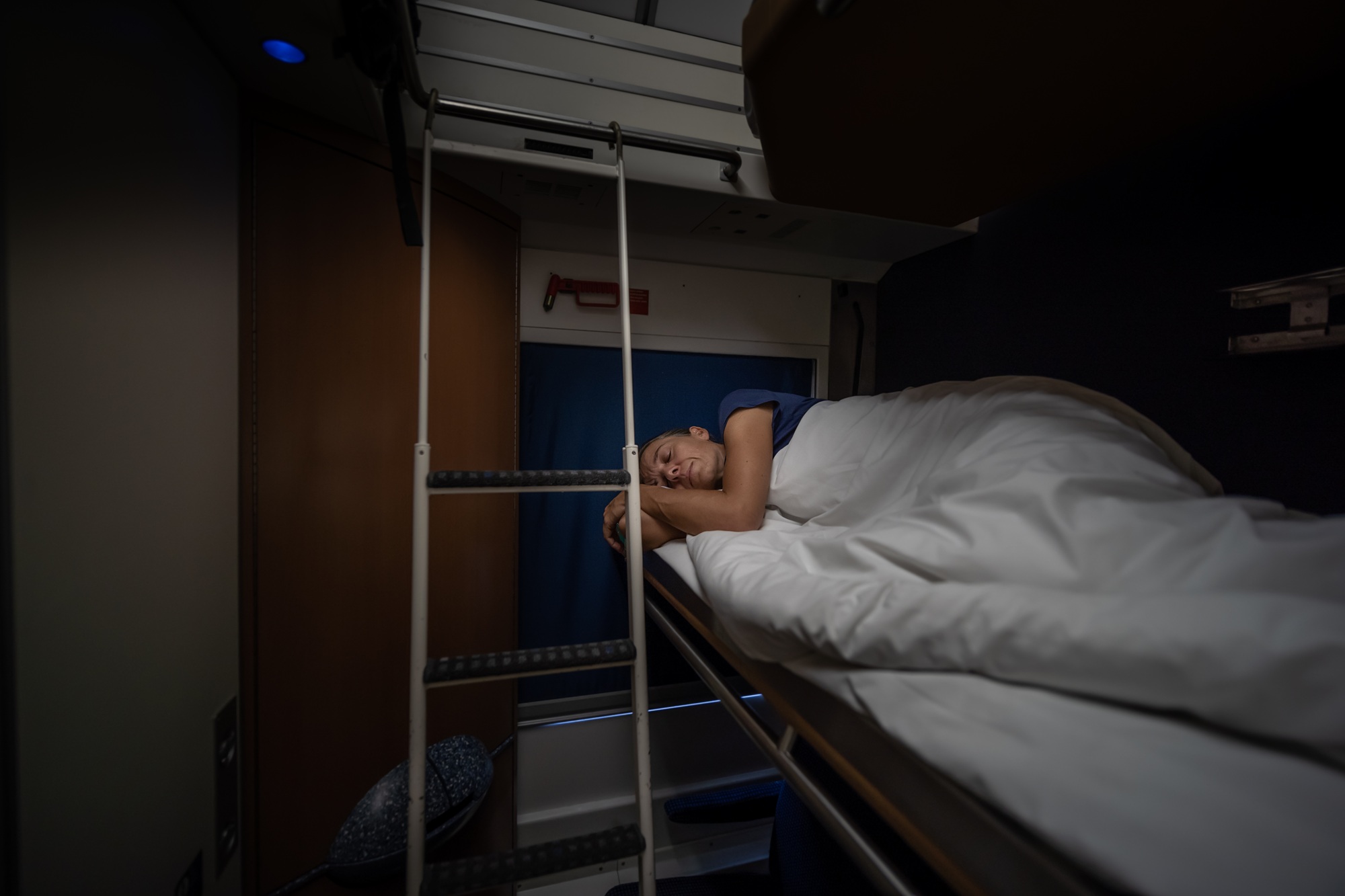Mensch liegt auf einem Bett im Liegewagen eines Nachtzuges und schläft