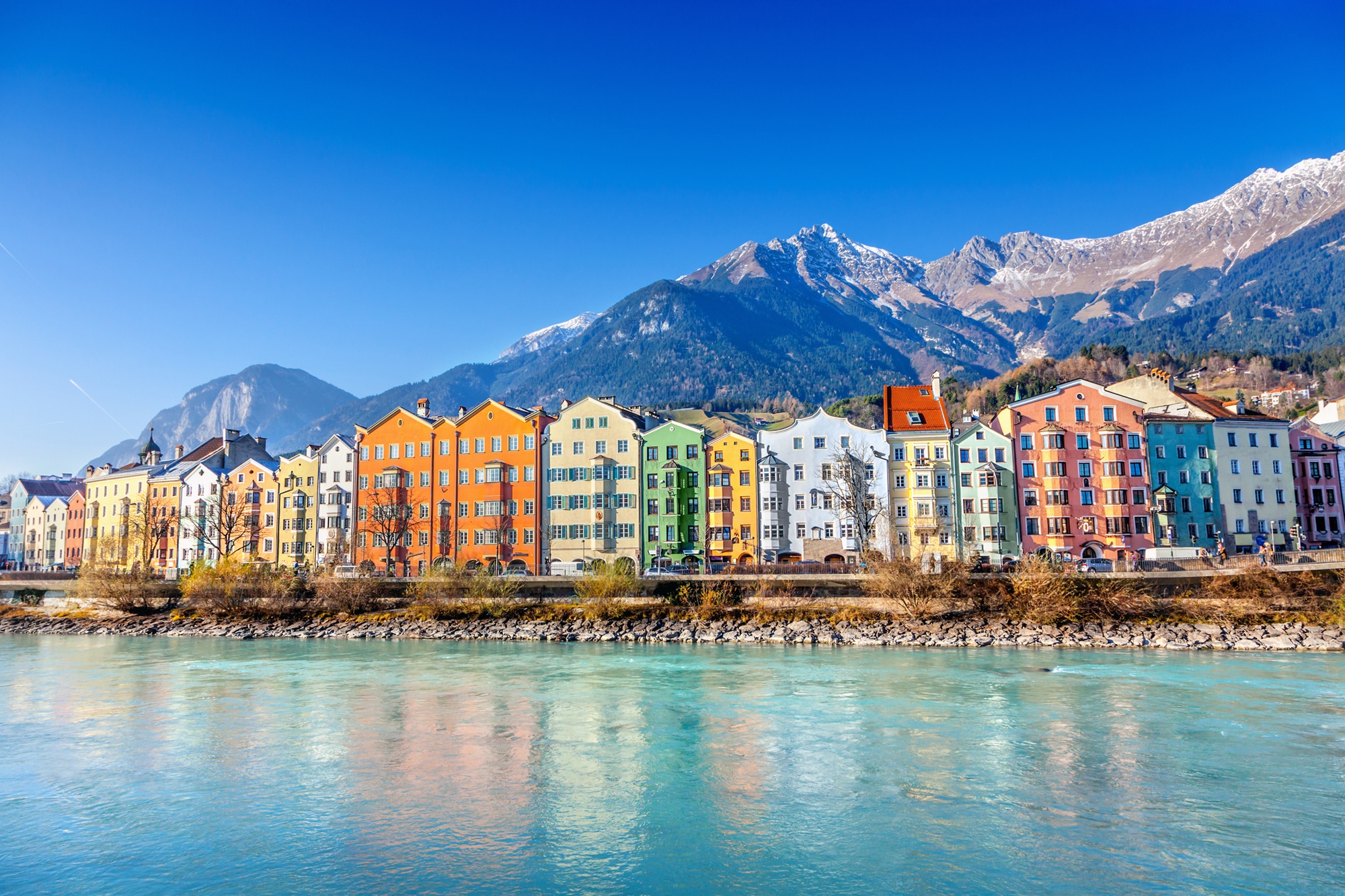 Blick auf das Stadtbild von Innsbruck mit Fluss im Vordergrund und Bergpanorama im Hintergrund