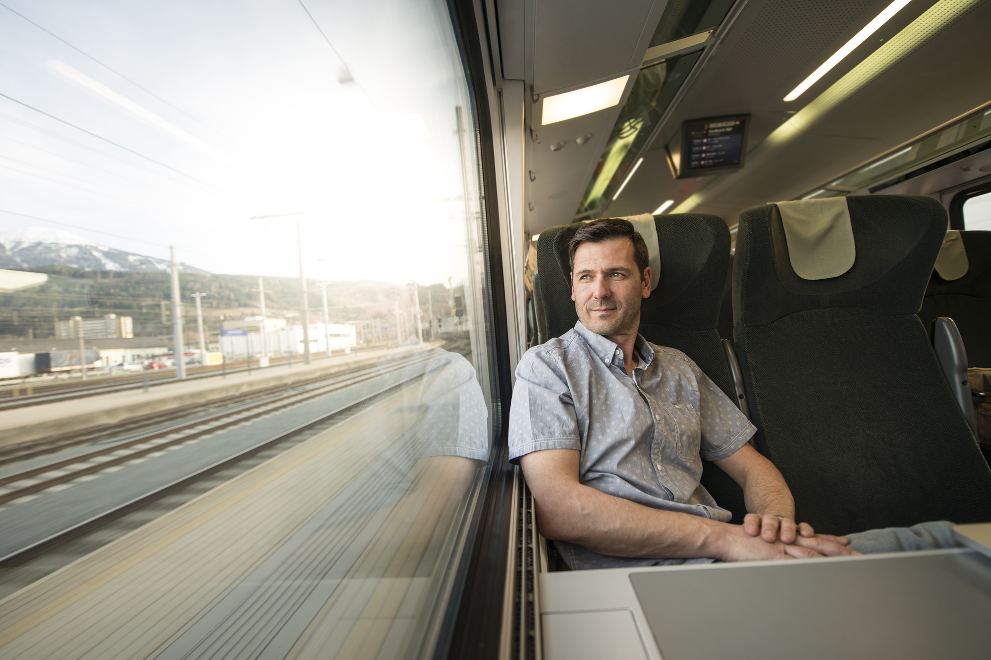 Ein Mann sitzt in einem Zug und schaut aus dem Fenster